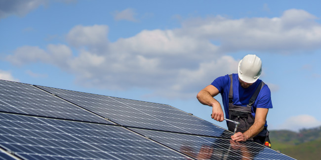 Artisan installant des panneaux solaires photovoltaïque sur le toit d'une maison