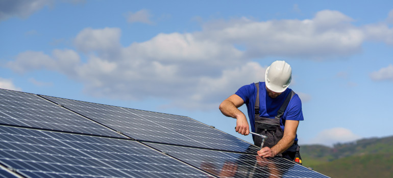 Artisan installant des panneaux solaires photovoltaïque sur le toit d'une maison