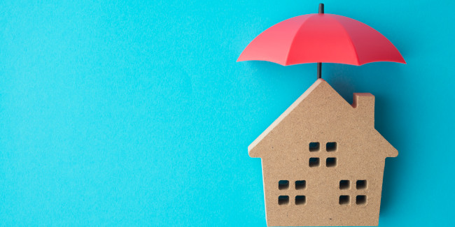 Franchise pour votre assurance habitation : parapluie rouge protégeant une maison en liège symbolisant la protection offerte par une assurance habitation