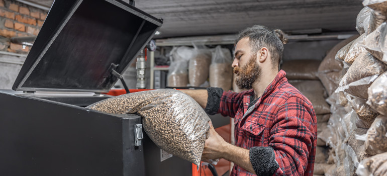 Remplissage d'une chaudière à granulés installée dans un garage avec un stock de pellet pour assurer une consommation annuelle