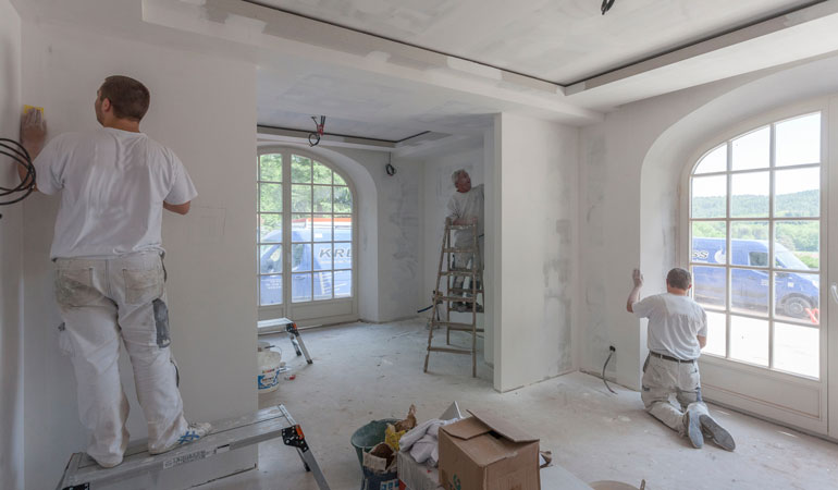 Rénovation d'une maison avec des ratisans préparant les murs avant peinture